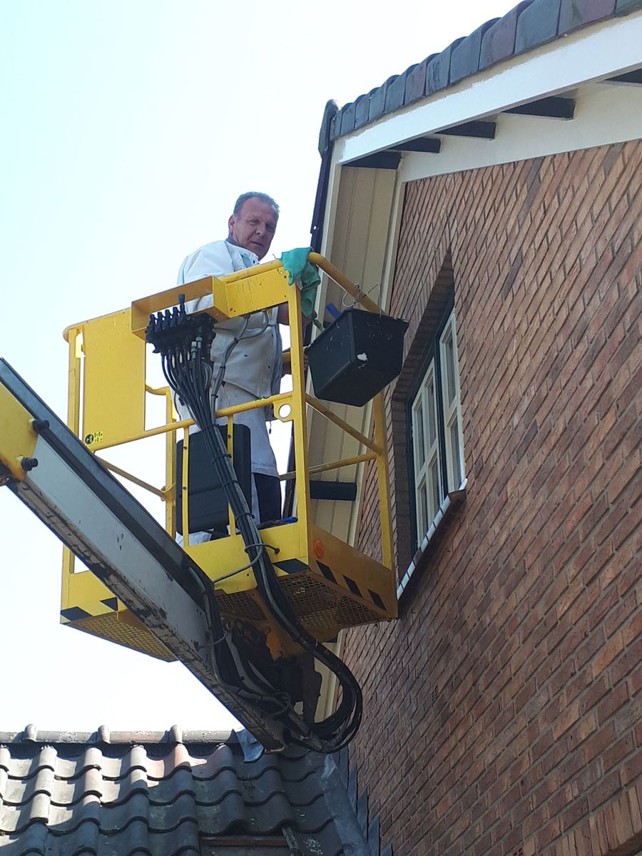 Gertjan lakt de dakgoot en boeidelen van een woning vanaf een hoogwerker